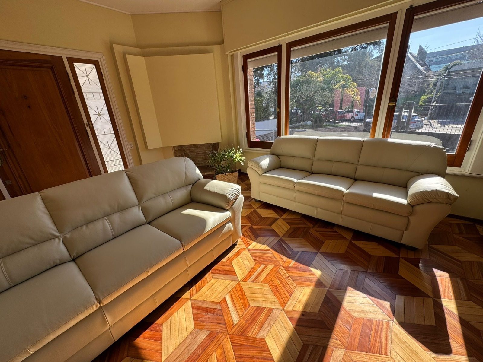 Living con sillones claros y luz natural por los ventanales